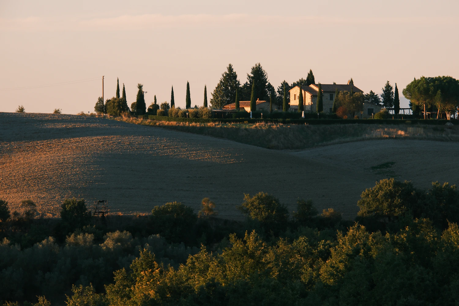 Casa de campo entre árboles y colinas al atardecer